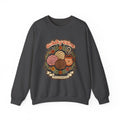 A comfortable cream-colored crewneck sweatshirt featuring a retro Mexican design depicting a steaming cup of Mexican coffee, surrounded by Mexican sweet breads, all with a “Cafecito y Chisme” twist.