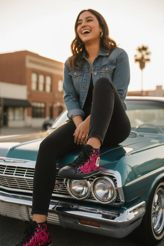 A Latina woman wearing black floral high-top sneakers with pink roses in a stylish Chicana-inspired fashion photoshoot