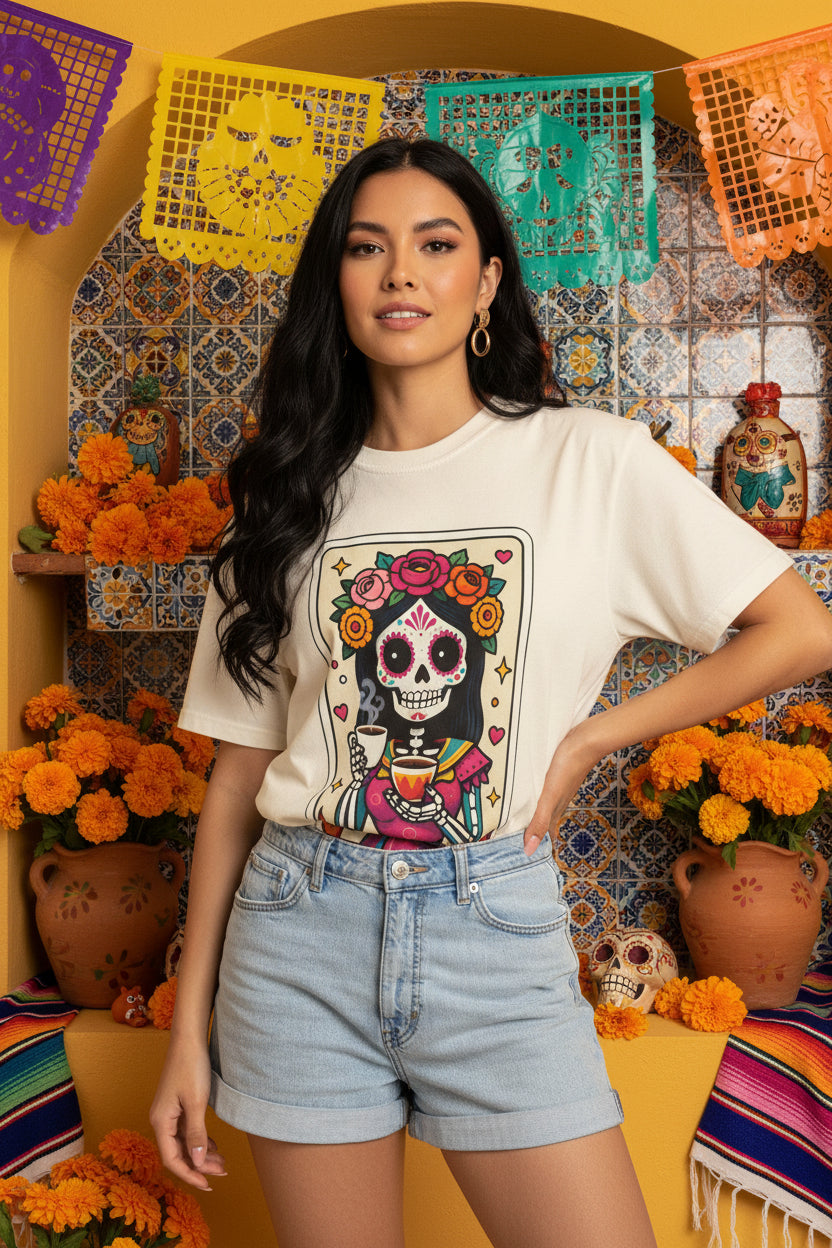 Vintage lotería card design on a t-shirt featuring a sugar skull calavera holding a coffee cup with the text La Chismosa.