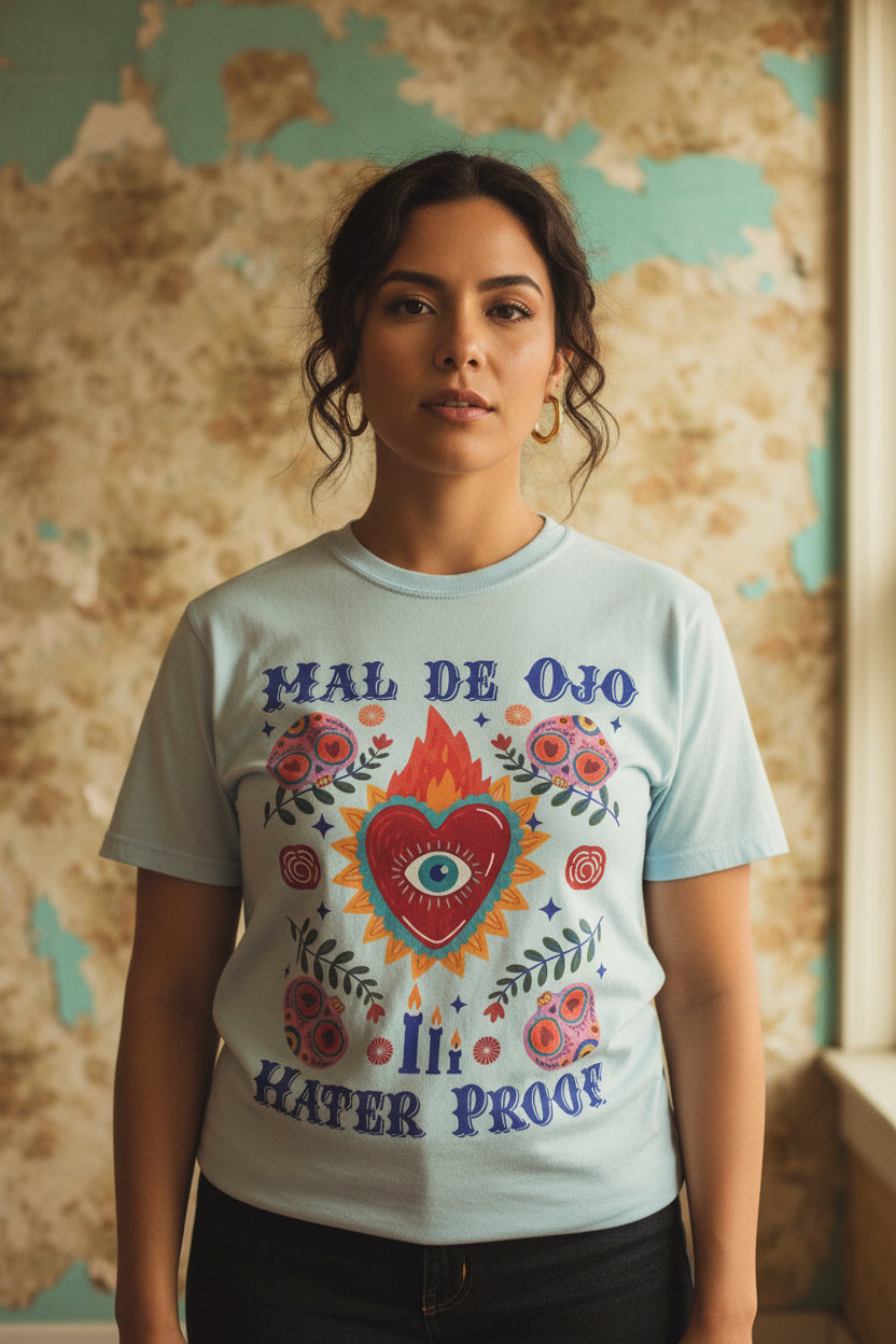 Heavyweight T-shirt featuring a colorful Sacred Heart graphic, a protective eye, and the phrase “Mal de Ojo Hater Proof.”
