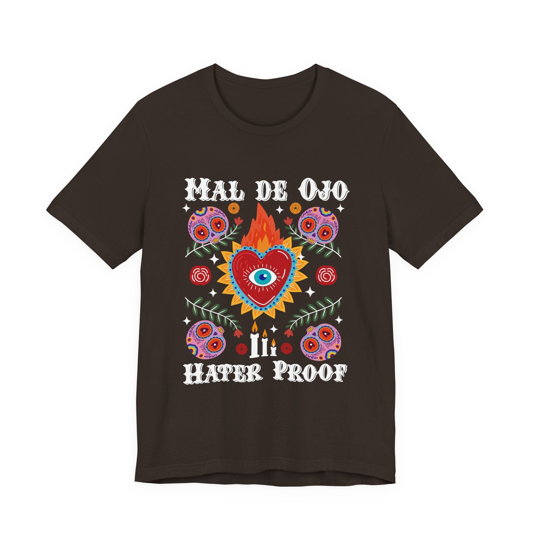 T-shirt featuring a colorful sacred heart with a blue eye in the center, sugar skulls, and the phrase “Mal de Ojo Hater Proof. Mexican tee, Mexican shirt