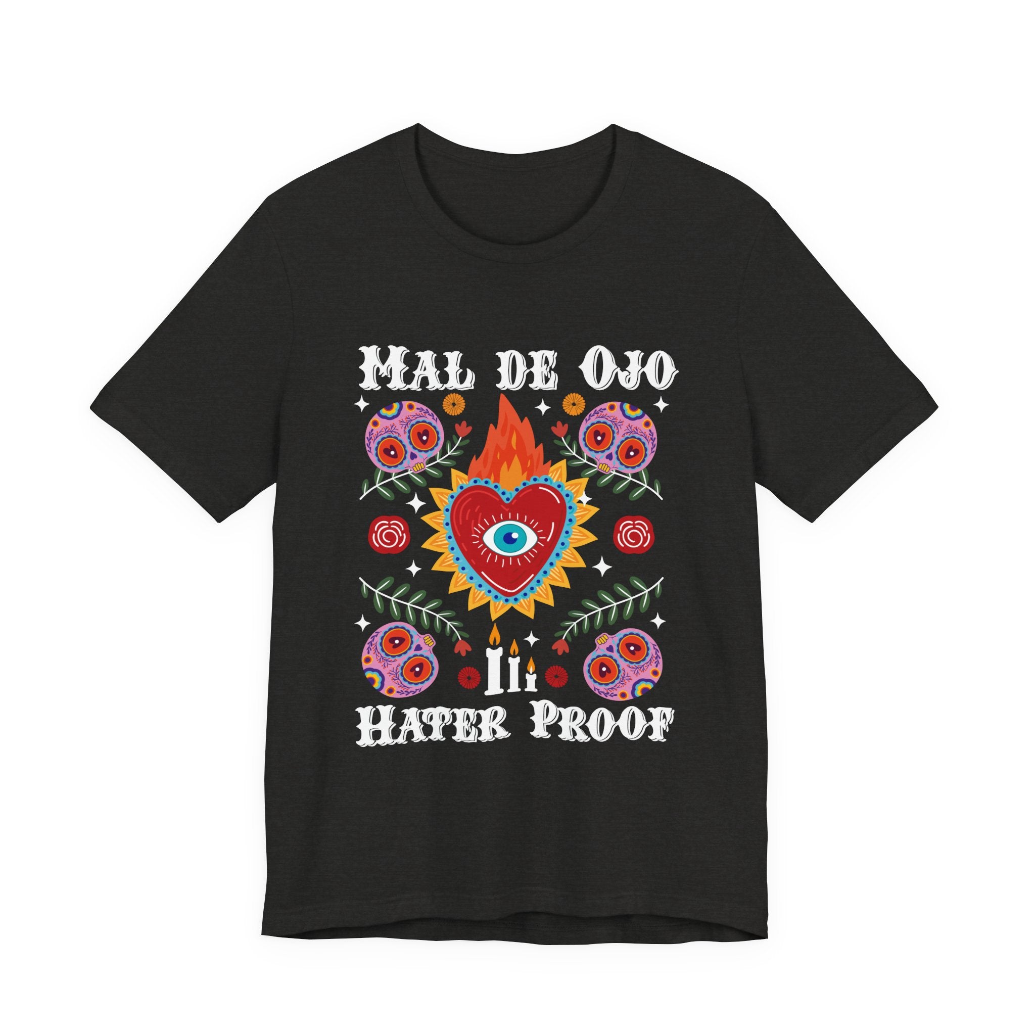 T-shirt featuring a colorful sacred heart with a blue eye in the center, sugar skulls, and the phrase “Mal de Ojo Hater Proof. Mexican tee, Mexican shirt