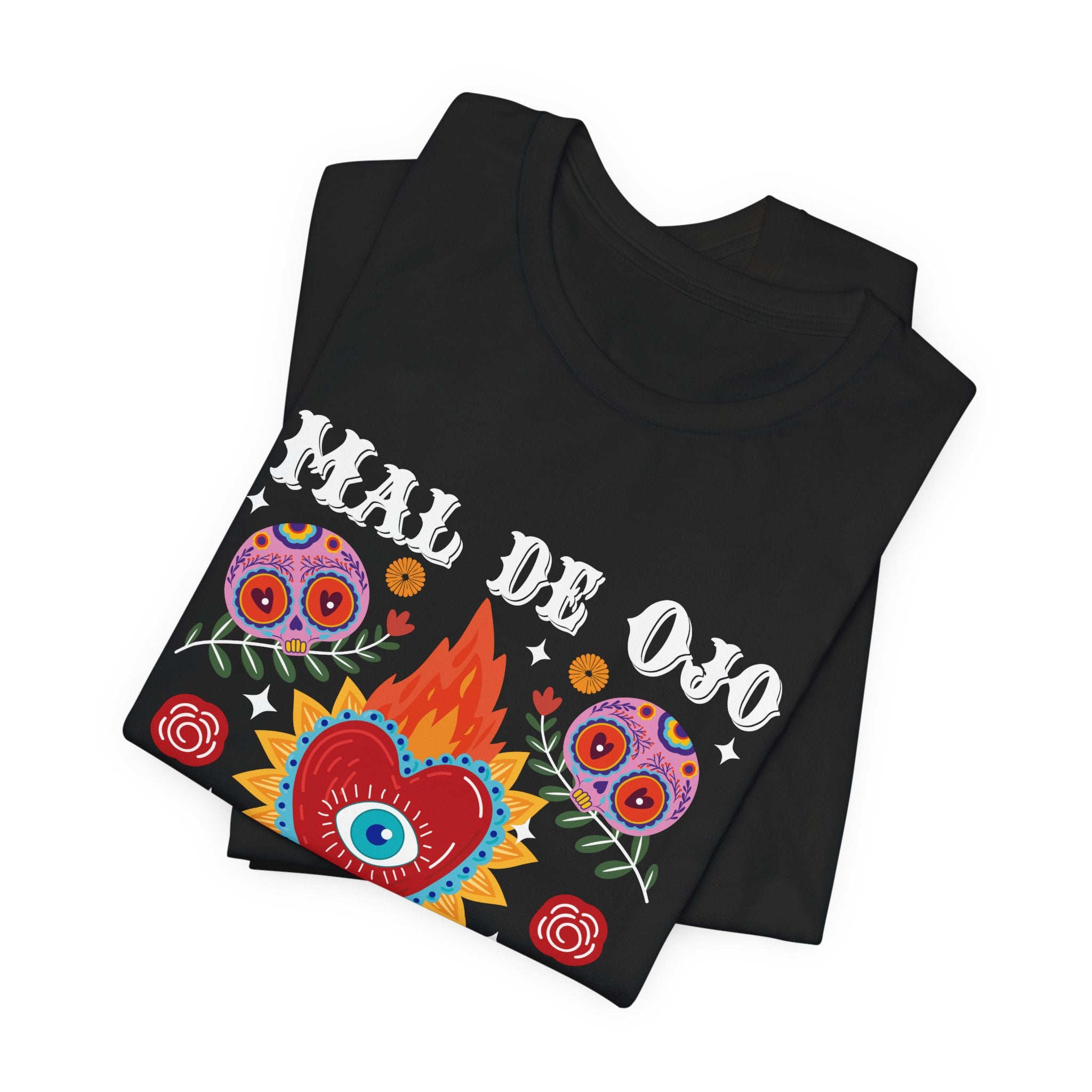 T-shirt featuring a colorful sacred heart with a blue eye in the center, sugar skulls, and the phrase “Mal de Ojo Hater Proof. Mexican tee, Mexican shirt