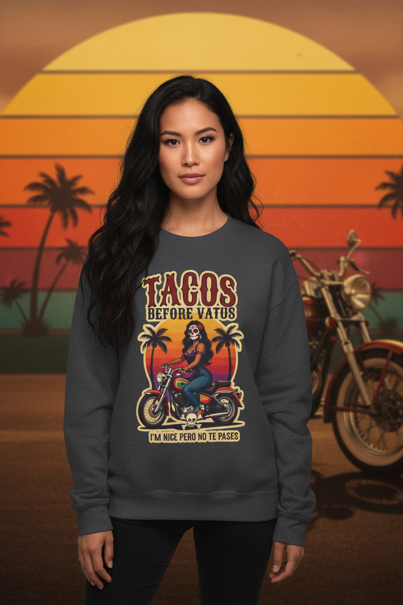 The bold “Tacos Before Vatos” lettering, featuring a vintage design of a Chicana riding a motorcycle at sunset, on a comfortable crew-neck sweatshirt.
