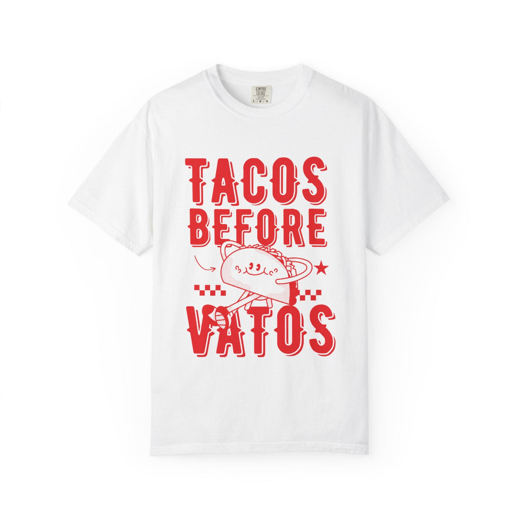 A cartoon character shaped like a taco, with the phrase “Tacos Before Vatos” printed in a bold, colorful retro 1970s font on a vintage white Comfort Colors T-shirt.