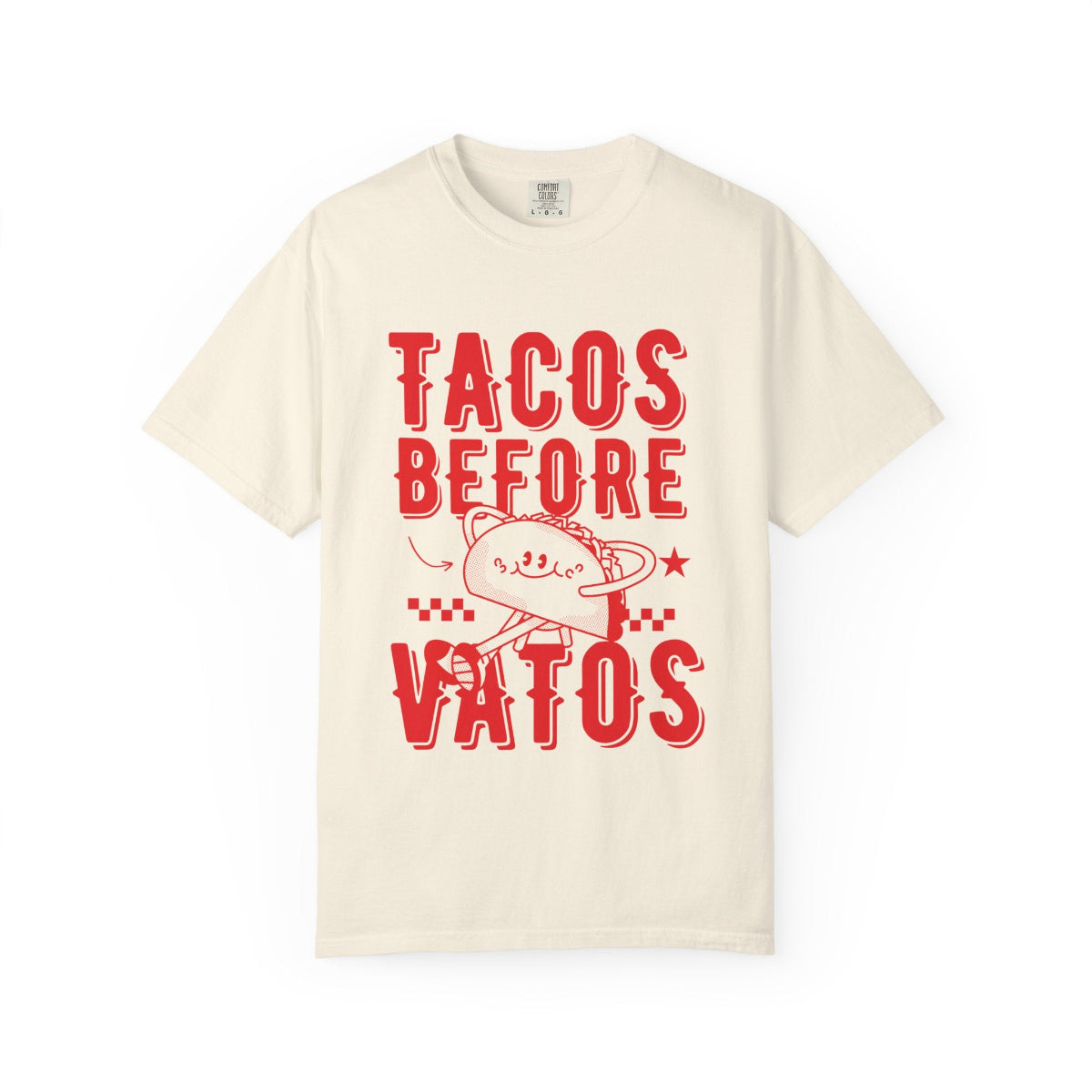 A cartoon character shaped like a taco, with the phrase “Tacos Before Vatos” printed in a bold, colorful retro 1970s font on a vintage Comfort Colors Tee.